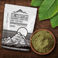 White BK Kratom bag laying on a wooden table beside a bowl of White Maeng Da Kratom Powder