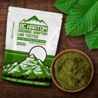 Green BC Kratom Bag laying on a wooden table next to a bowl of Green Sumatra Kratom Powder