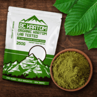 Green BC Kratom Bag laying on a wooden table next to a bowl of Spring Blend Kratom Powder