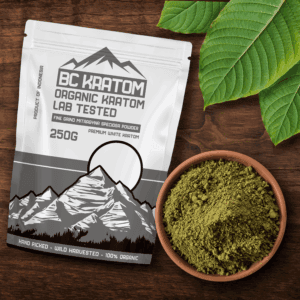 White BC Kratom bag laying on a wooden table next to a bowl of White Jongkong Kratom Powder